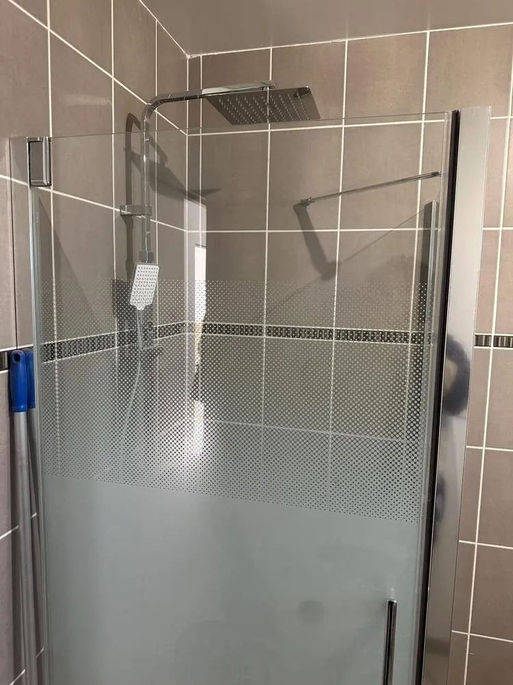 Douche à l'italienne avec paroi vitrée, colonne de douche à pommeau carré et faïence grise